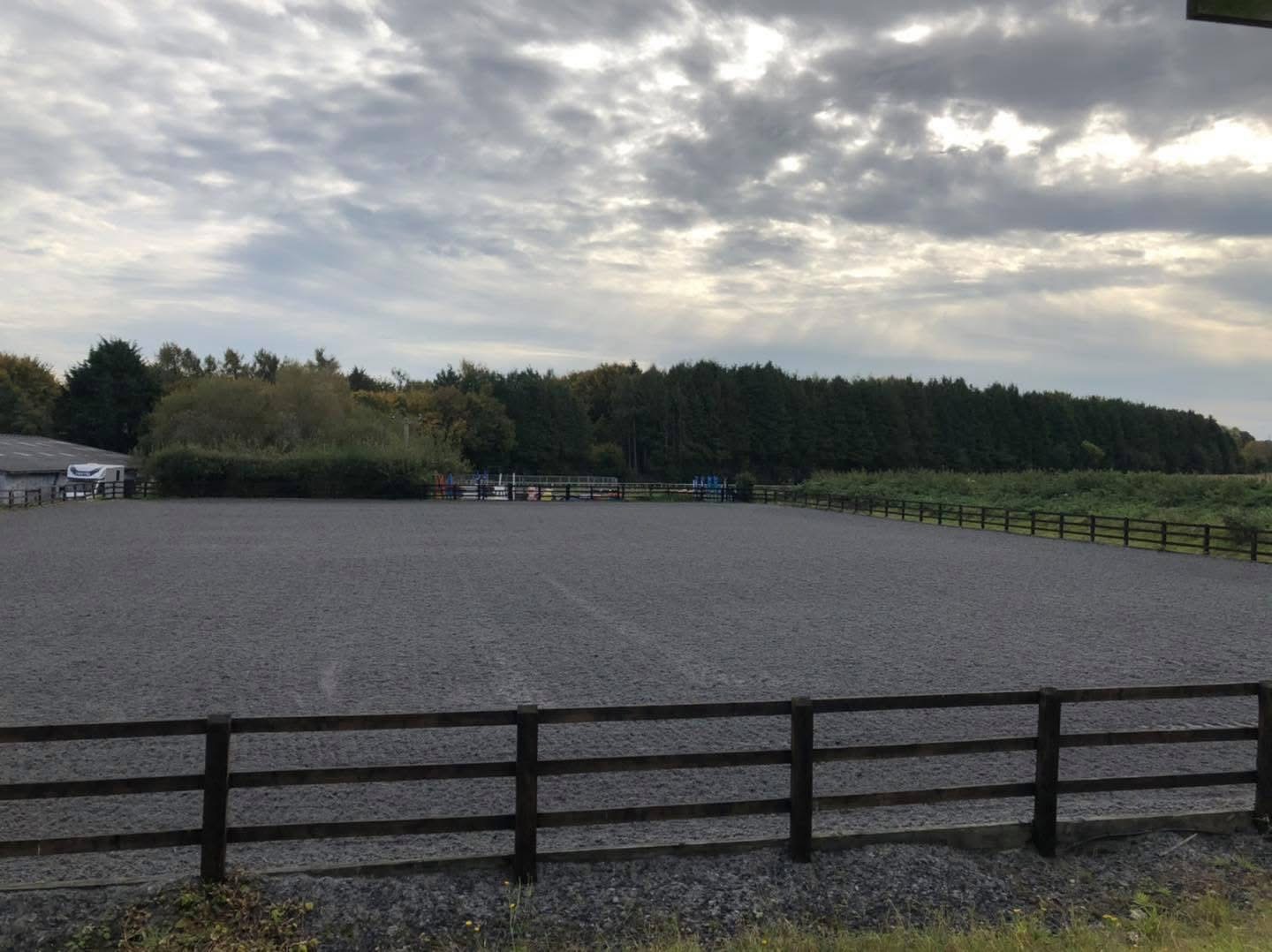 Outdoor riding arena with jumps set up at the far end